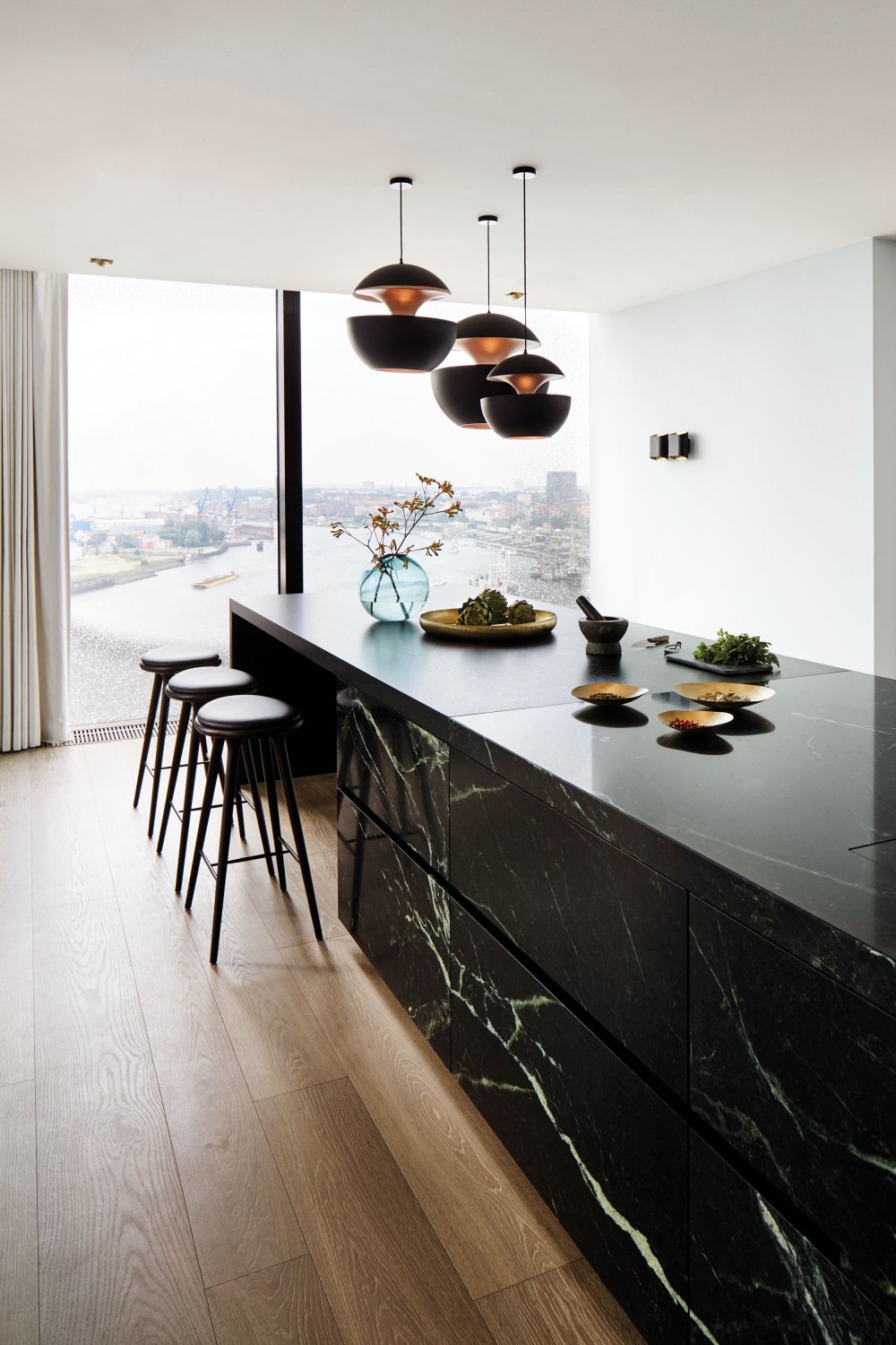 Designküche im Loft an der Elbphilharmonie mit Kücheninsel aus Serpentinit und Blick über Hamburg